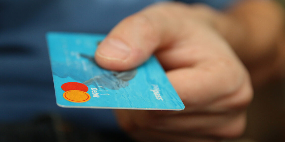 person handing over Mastercard debit card to complete a transaction