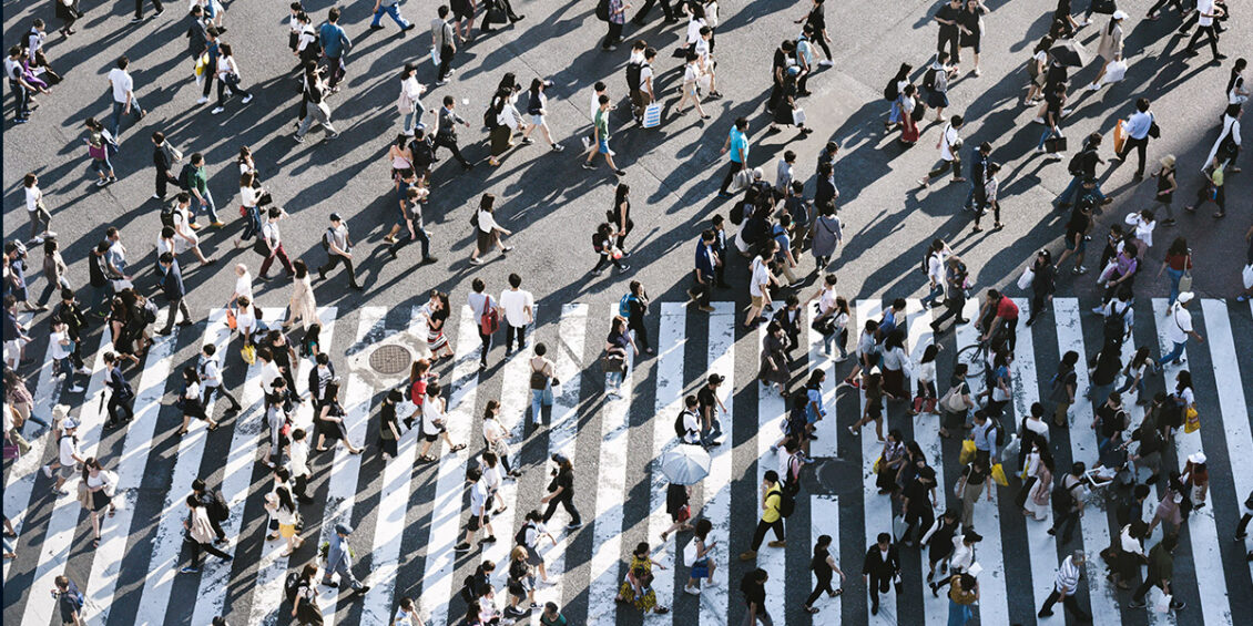 people walking across and around a pedestrian crossing in a major city