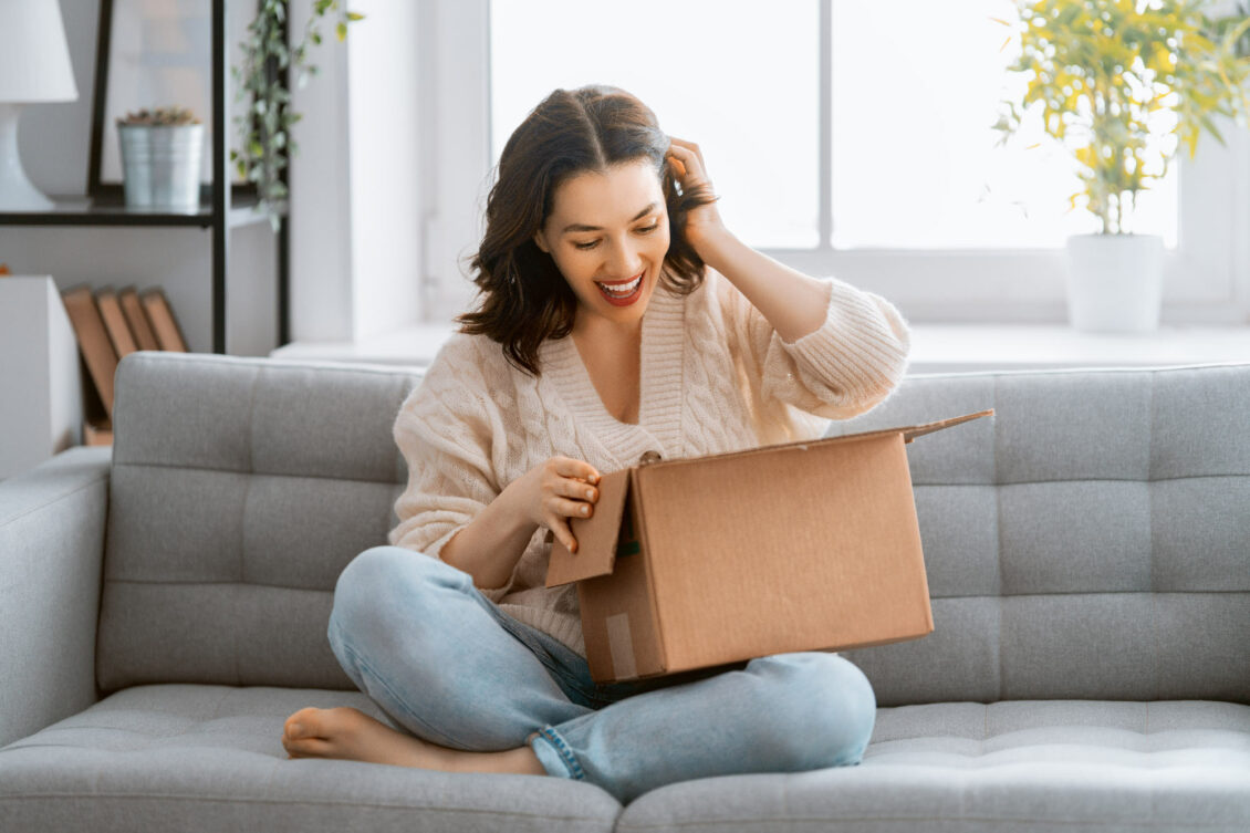 A woman opening a cardboard box on the sofa