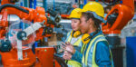 Factory workers in a manufacturing plant checking information on a laptop